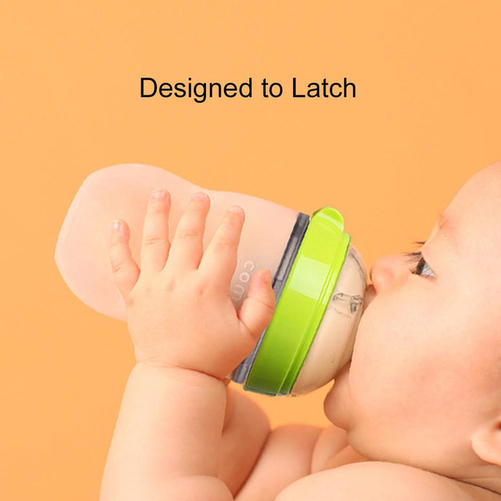 Baby drinking from a green Comotomo baby bottle with soft silicone design