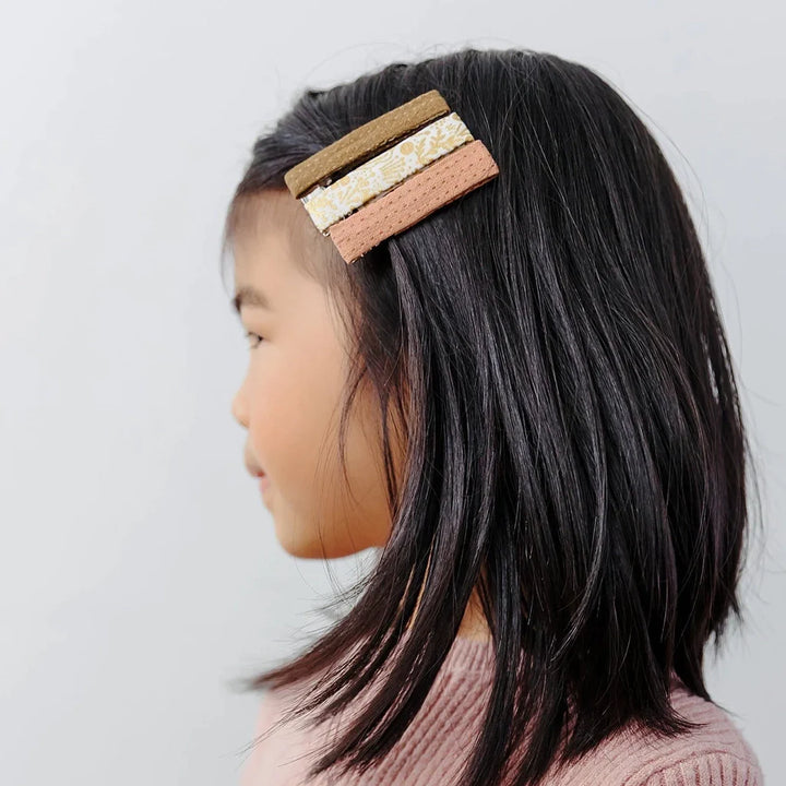 Large cute hair clips modeled by parent holding child.