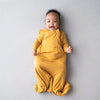 Baby wearing Kyte Baby Sleep Sack in Marigold yellow