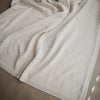 white knitted blanket laid out across bed