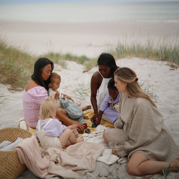 moms and babies on beach with blankets