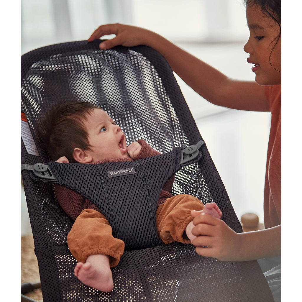 sister looking at infant in BabyBjorn baby bouncer bliss in anthracite
