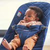 close up of baby lying in blue cotton quilt bouncer bliss by BabyBjorn