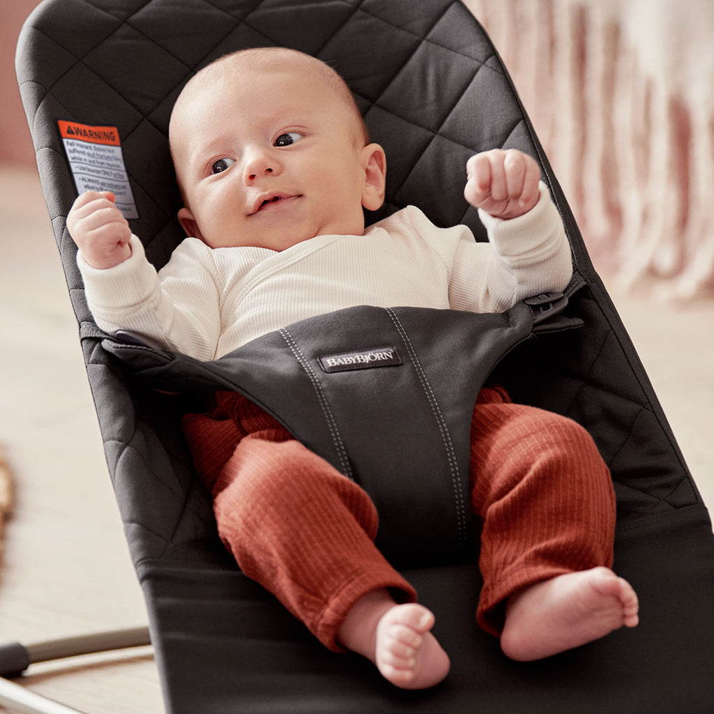 baby smiling in black cotton quilt bouncer bliss by baby bjorn