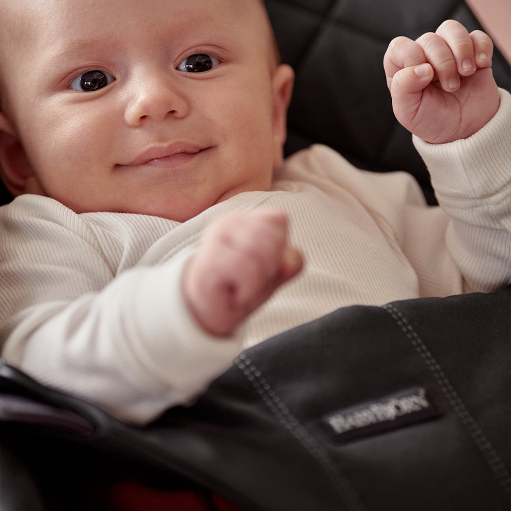 close up of infant in black cotton babybjorn best baby bouncer