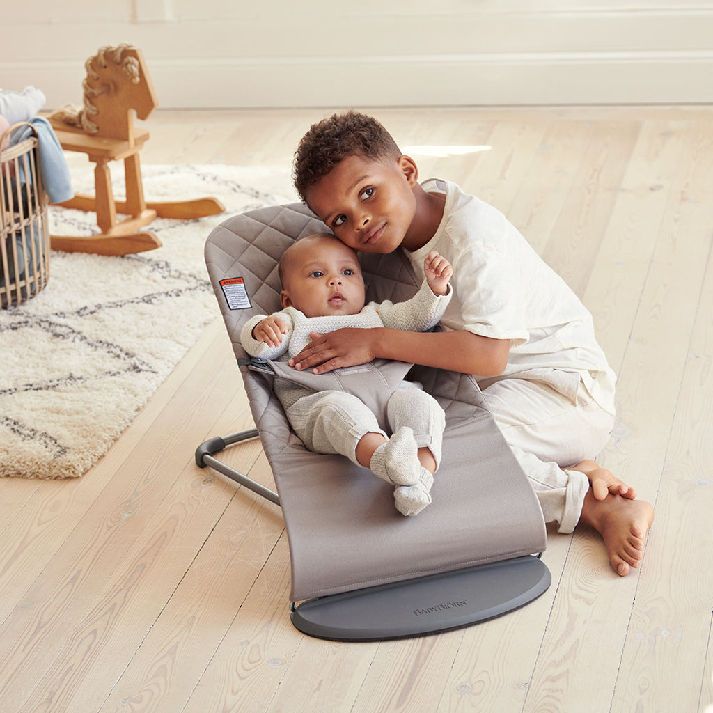 son hugging baby in sand grey cotton babybjorn bouncer