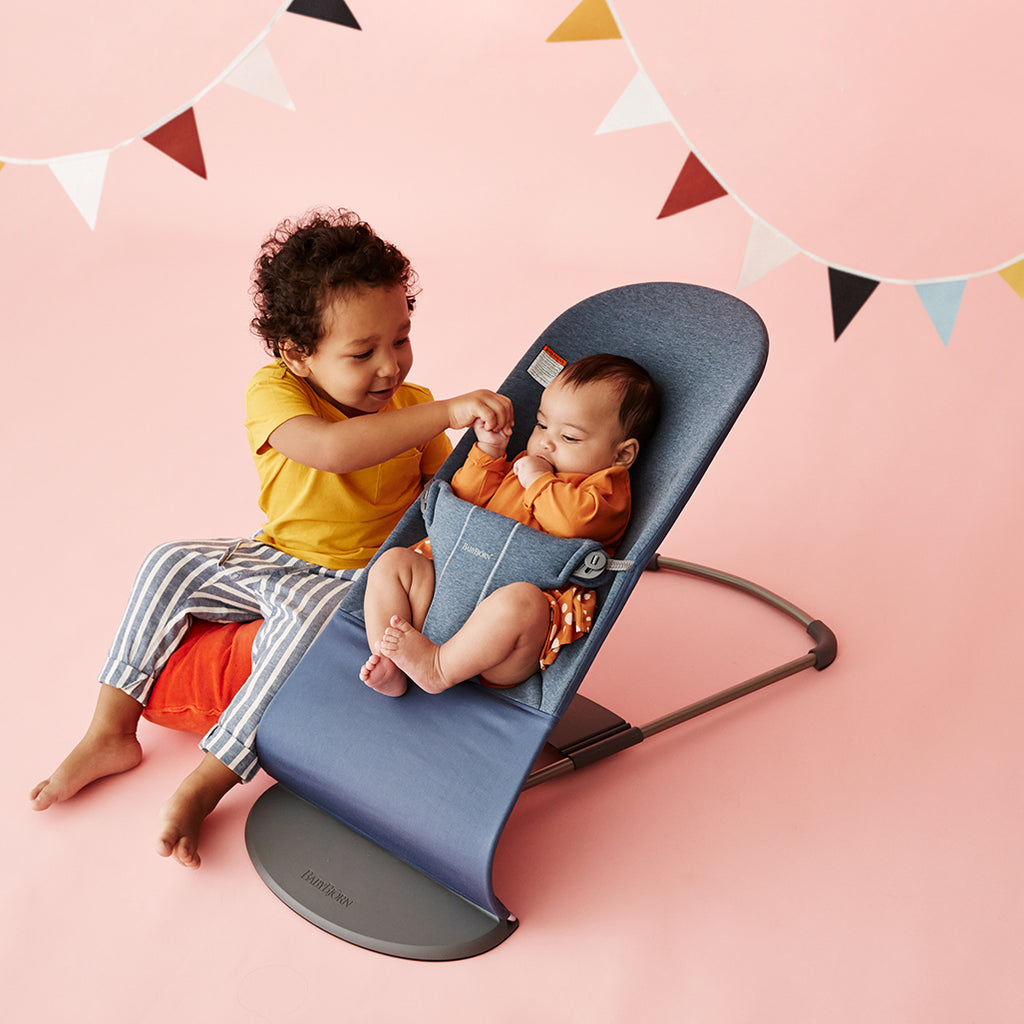baby playing with sibling in bouncer bliss by Babybjorn dove blue jersey