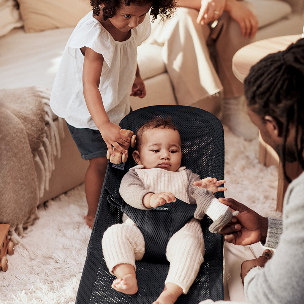 dad and daughter playing with infant in black mesh bouncer by Baby Bjorn