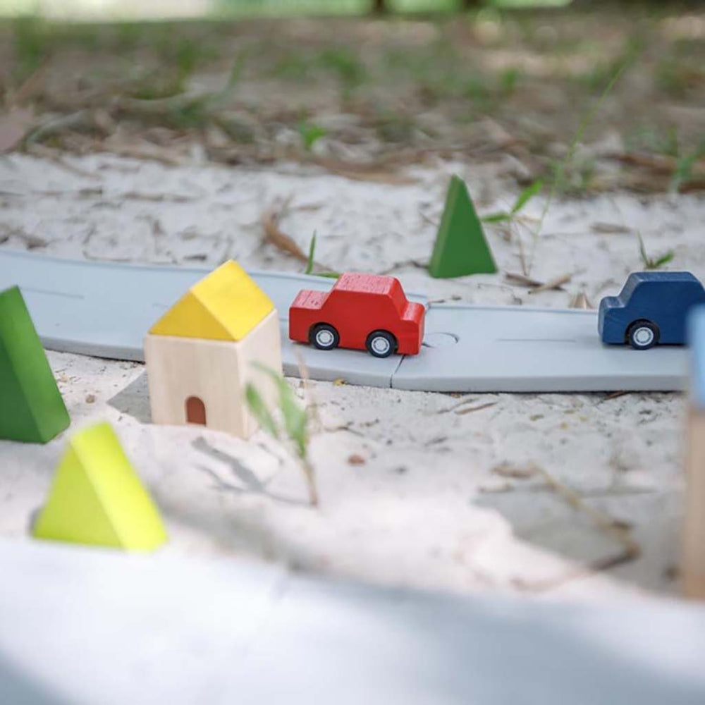 A child playing with Plan Toys rubber expansion kit, fitting tracks together to create a fun toy car system.