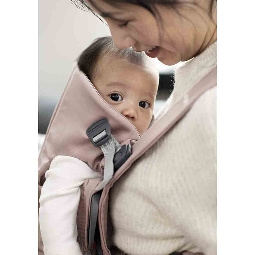 mom smiling with infant in mini baby carrier by babybjorn