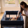 Mom with Baby sleeping in UPPAbaby Remi Playard with Zip-on Bassinet