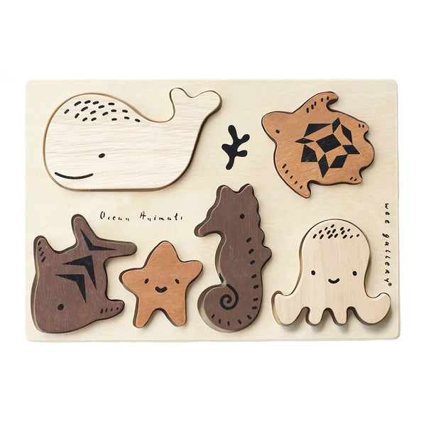 Wee Gallery Ocean Animals Wooden Tray Puzzle. Six ocean animal pieces in various shades of brown with black paint marking for accents. Natural wooden tray with cut outs in the shapes of the animal pieces.