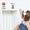 Wee Gallery Panda Wooden Stacker Children's Stacking Game. Lifestyle photo of child reaching for assembled stacker on shelf next to Wee Gallery Bear Stacker.