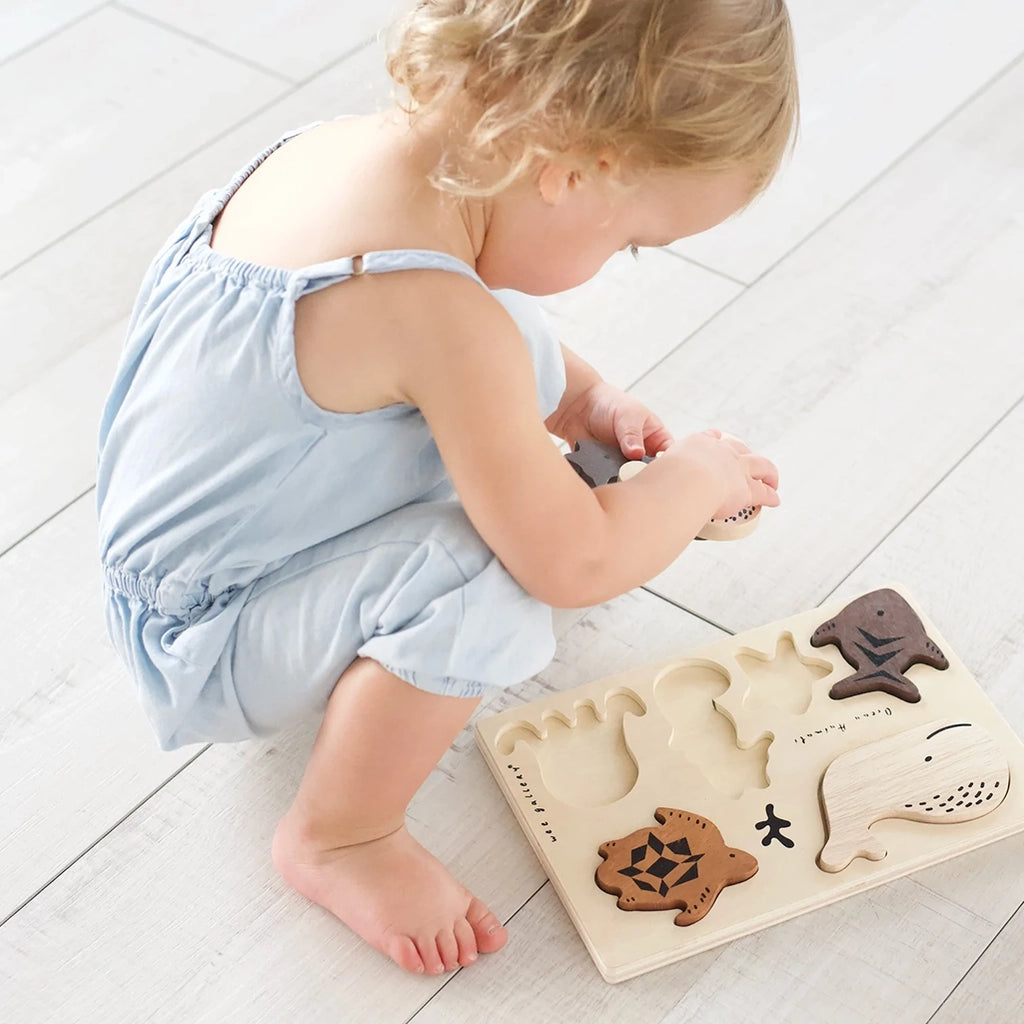 Wee Gallery Ocean Animals Wooden Tray Puzzle. Lifestyle image of a child playing with the tray puzzle.
