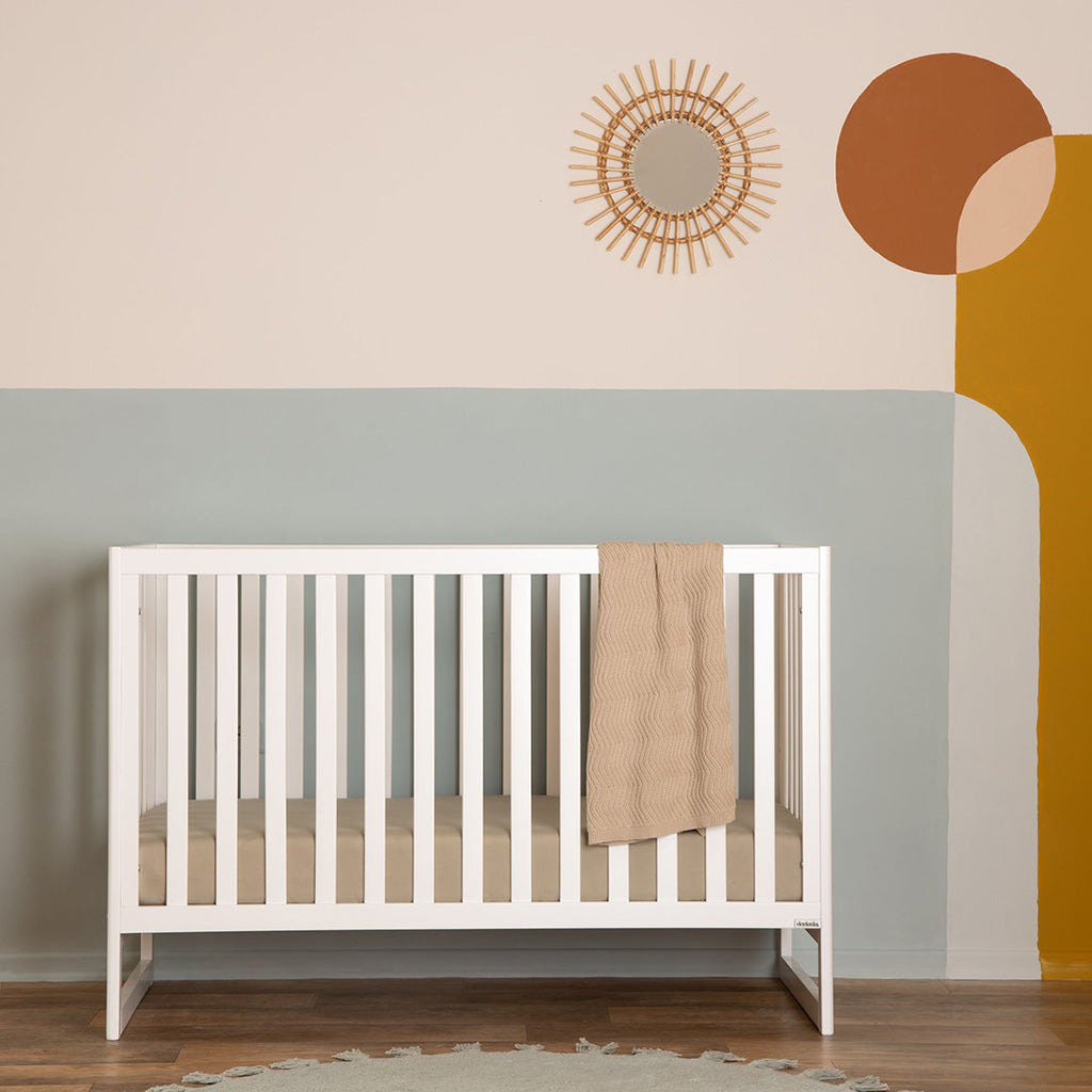 Lifestyle image of the Austin 3-in-1 Convertible Crib in a nursery. Toddler bed rails
